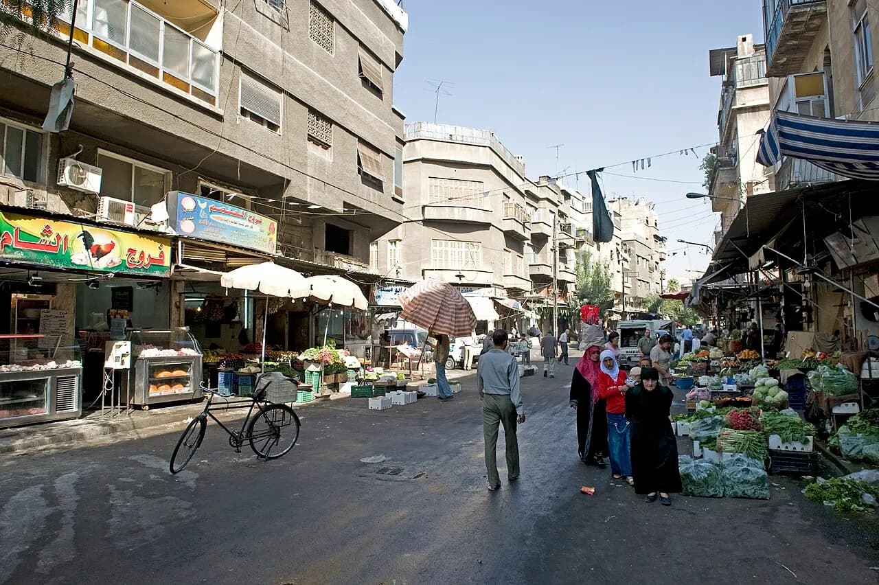 Shops, apartment buildings and pedestrians on a side street off Khaled Ibn Al Walid Street in Damascus, photographed in September 2008