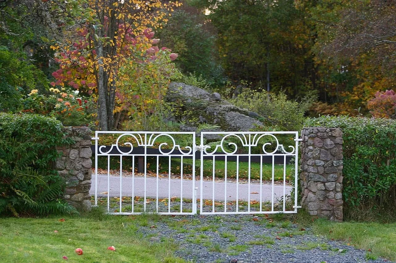White metal garden gate between stone posts in Klavreström, Sweden, photographed in October 2006