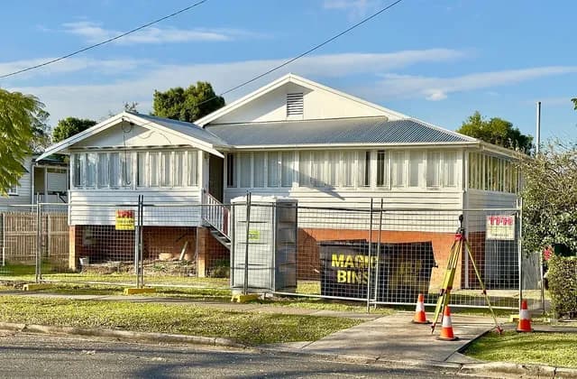 House exterior behind temporary fencing, with a tripod, cones and portable toilet in Sherwood, Queensland, Australia