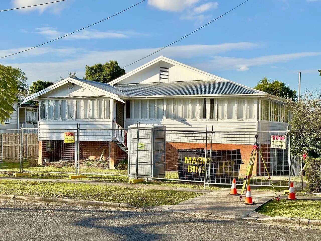 House exterior behind temporary fencing, with a tripod, cones and portable toilet in Sherwood, Queensland, Australia