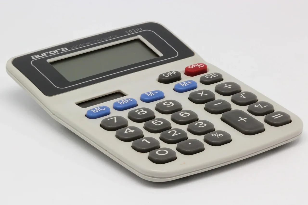 Desktop calculator with a blank display, grey number keys, blue memory keys and a red on key