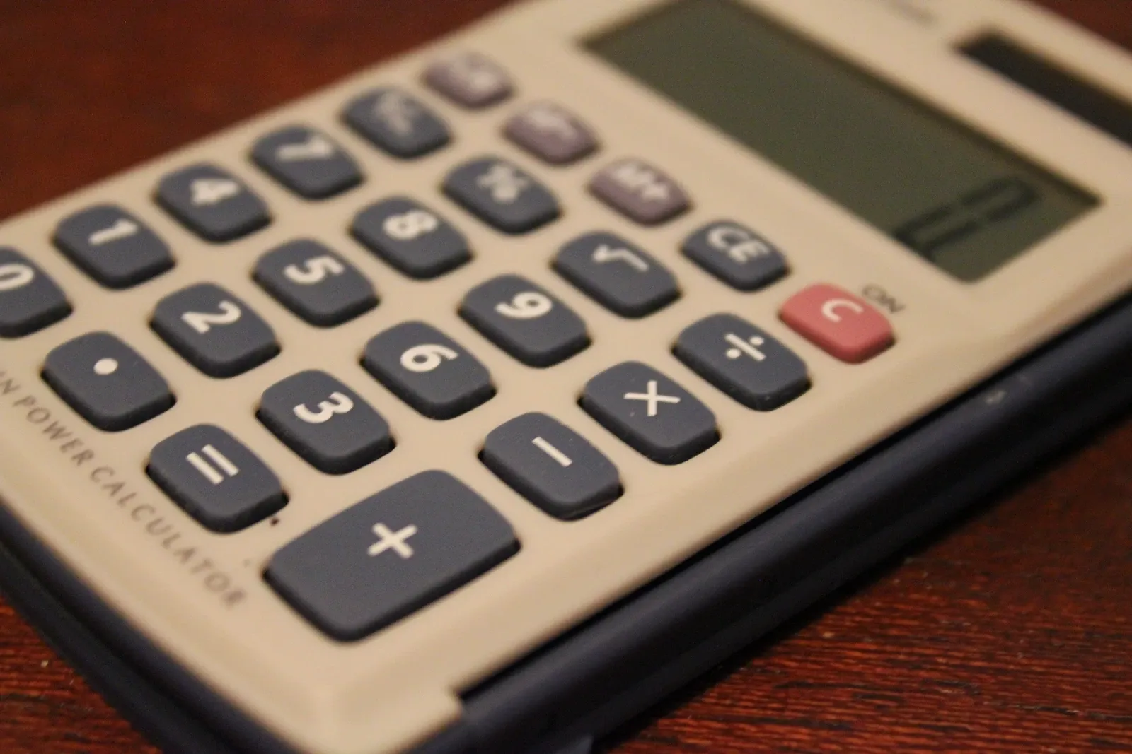 Close view of calculator keys on a wooden surface, illustrative photograph