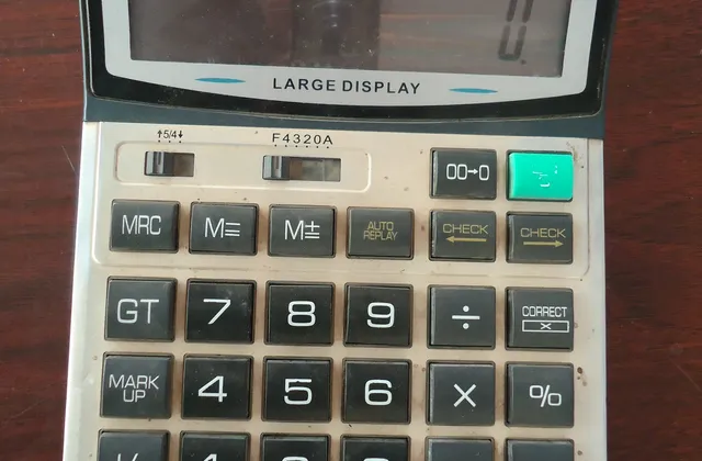 Desktop calculator on a wooden surface with zero shown on its display