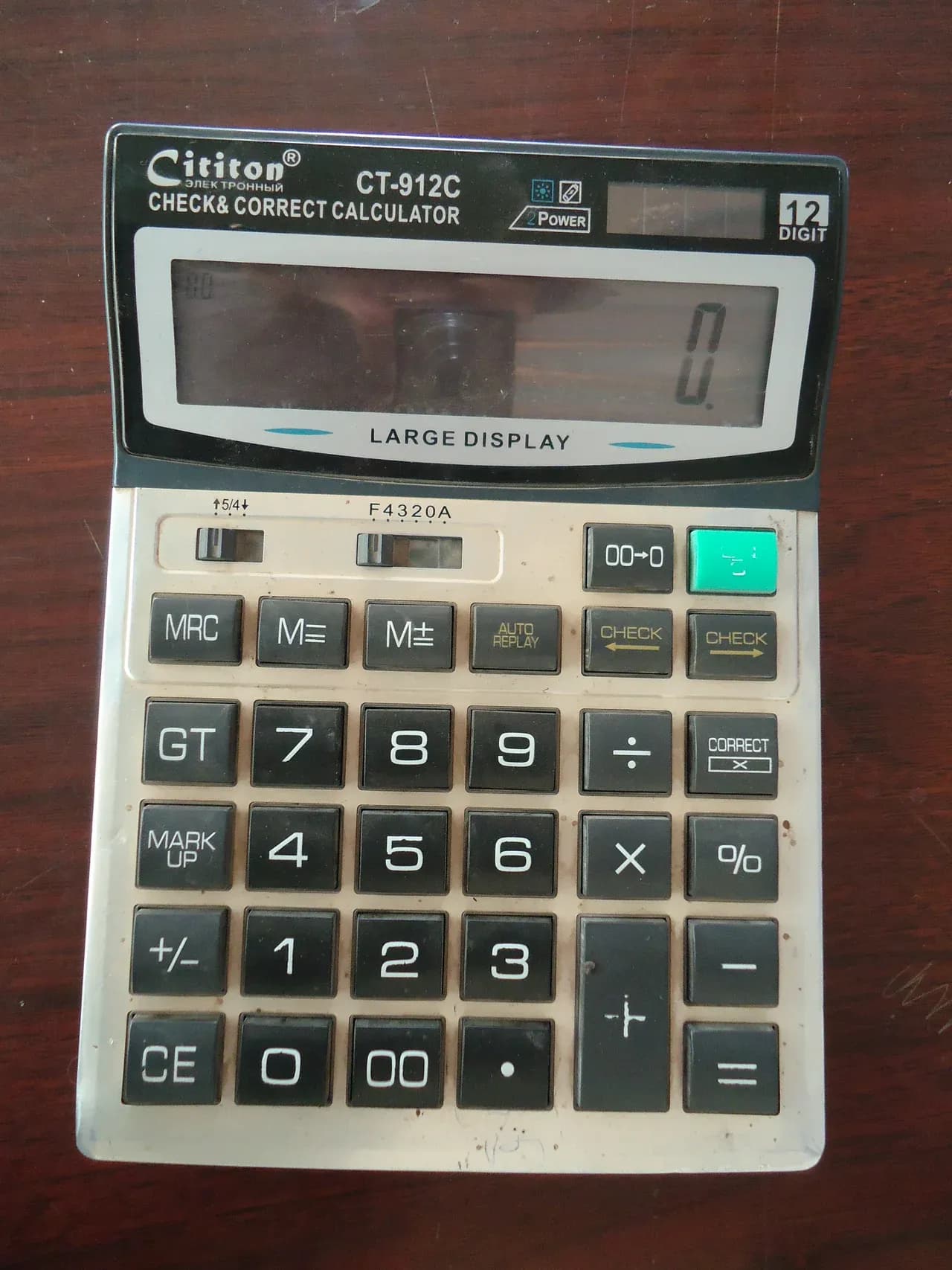 Desktop calculator on a wooden surface with zero shown on its display