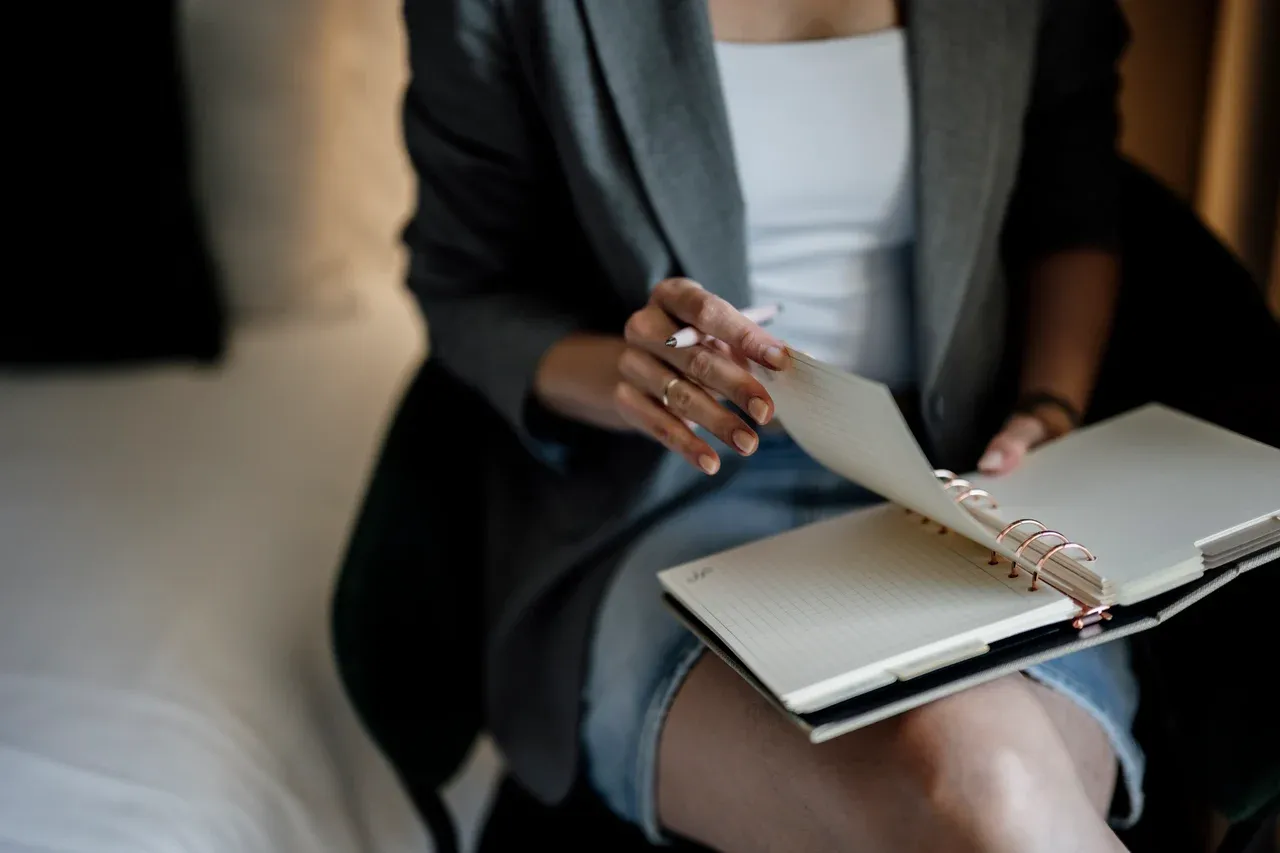 Person turning a page in an open ring notebook while holding a pen