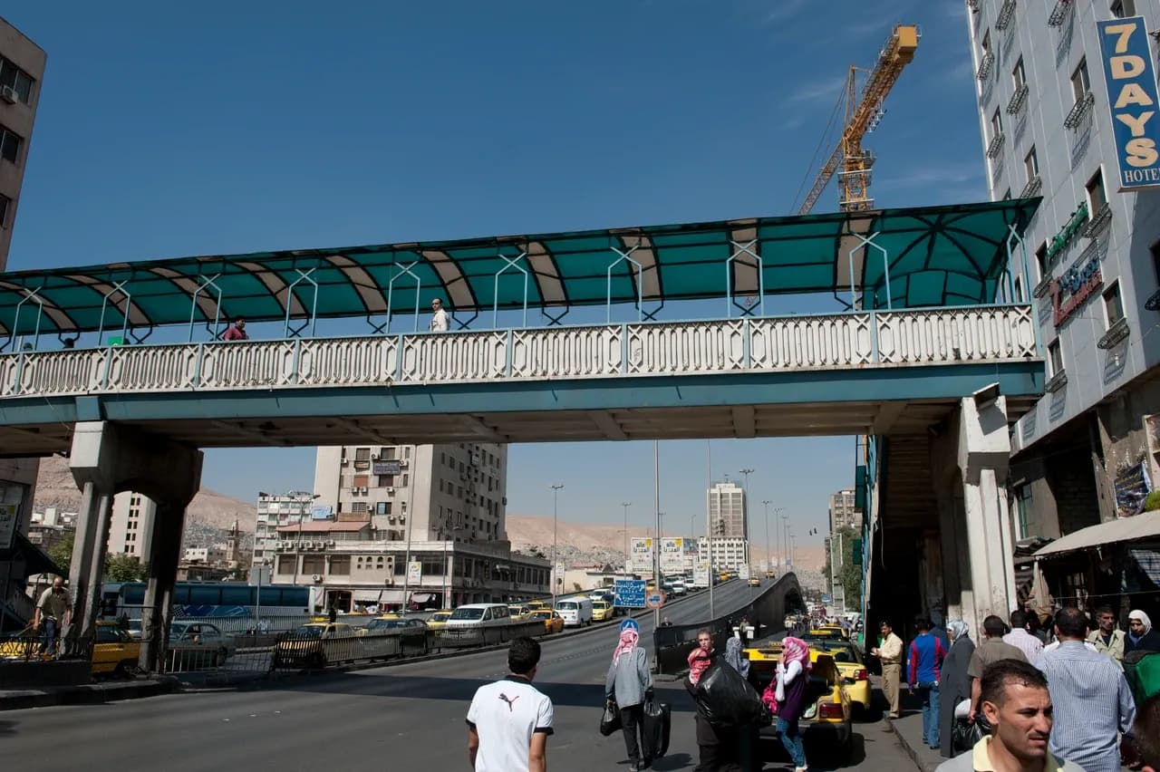Covered pedestrian bridge, traffic and buildings on Al-Thawra Street in Damascus, photographed in October 2010