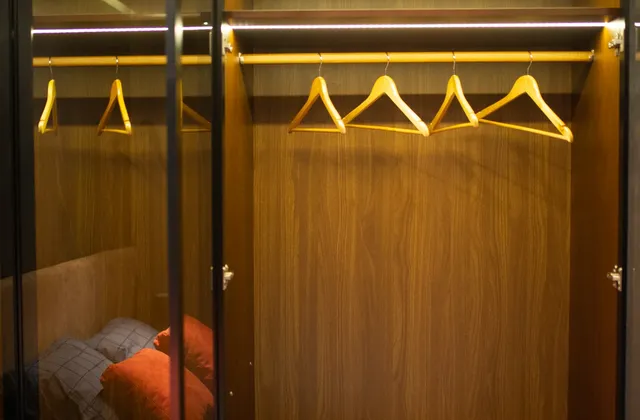 Open wardrobe with shelves, hangers, glazed doors and cushions, photographed in February 2022