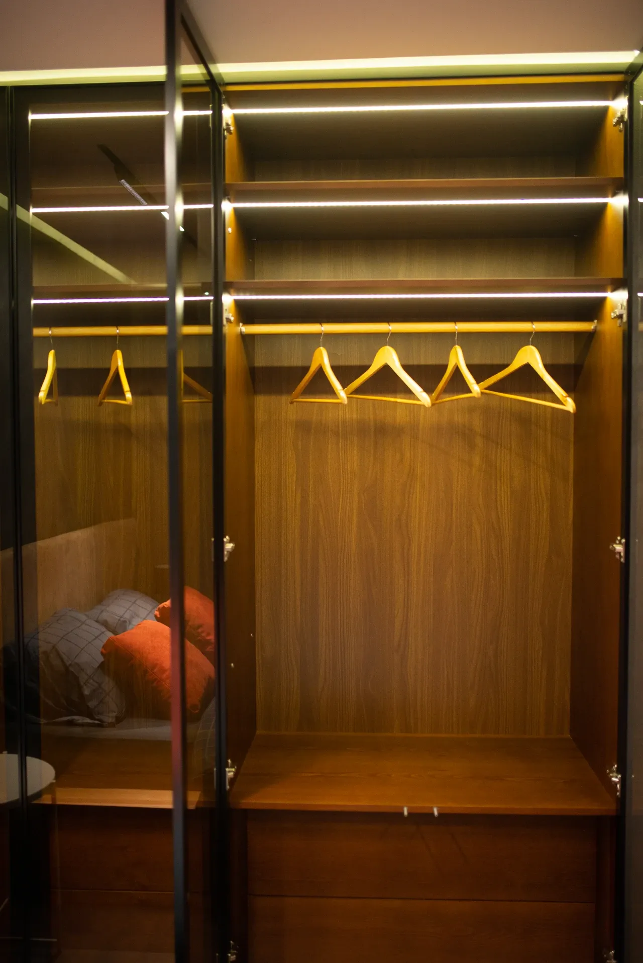 Open wardrobe with shelves, hangers, glazed doors and cushions, photographed in February 2022