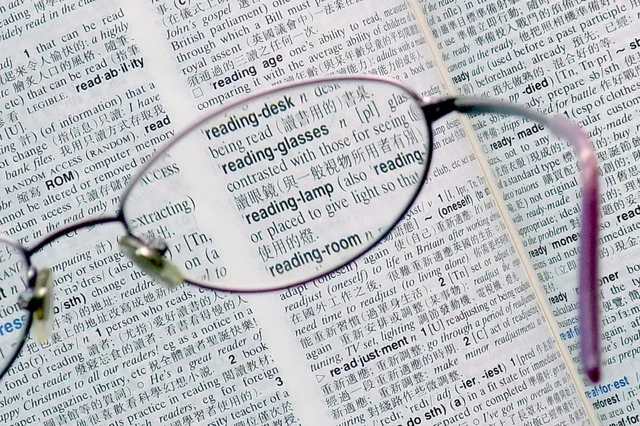 Reading glasses resting on an open bilingual dictionary, photographed in February 2011