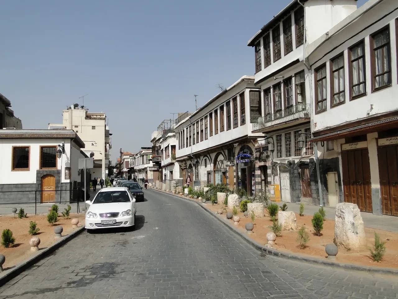 Bab Sharqi Street in Damascus lined with shop fronts and buildings, photographed in 2010.