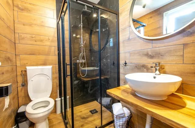 Bathroom with wood-effect wall finishes, glass shower enclosure and basin, photographed in September 2021