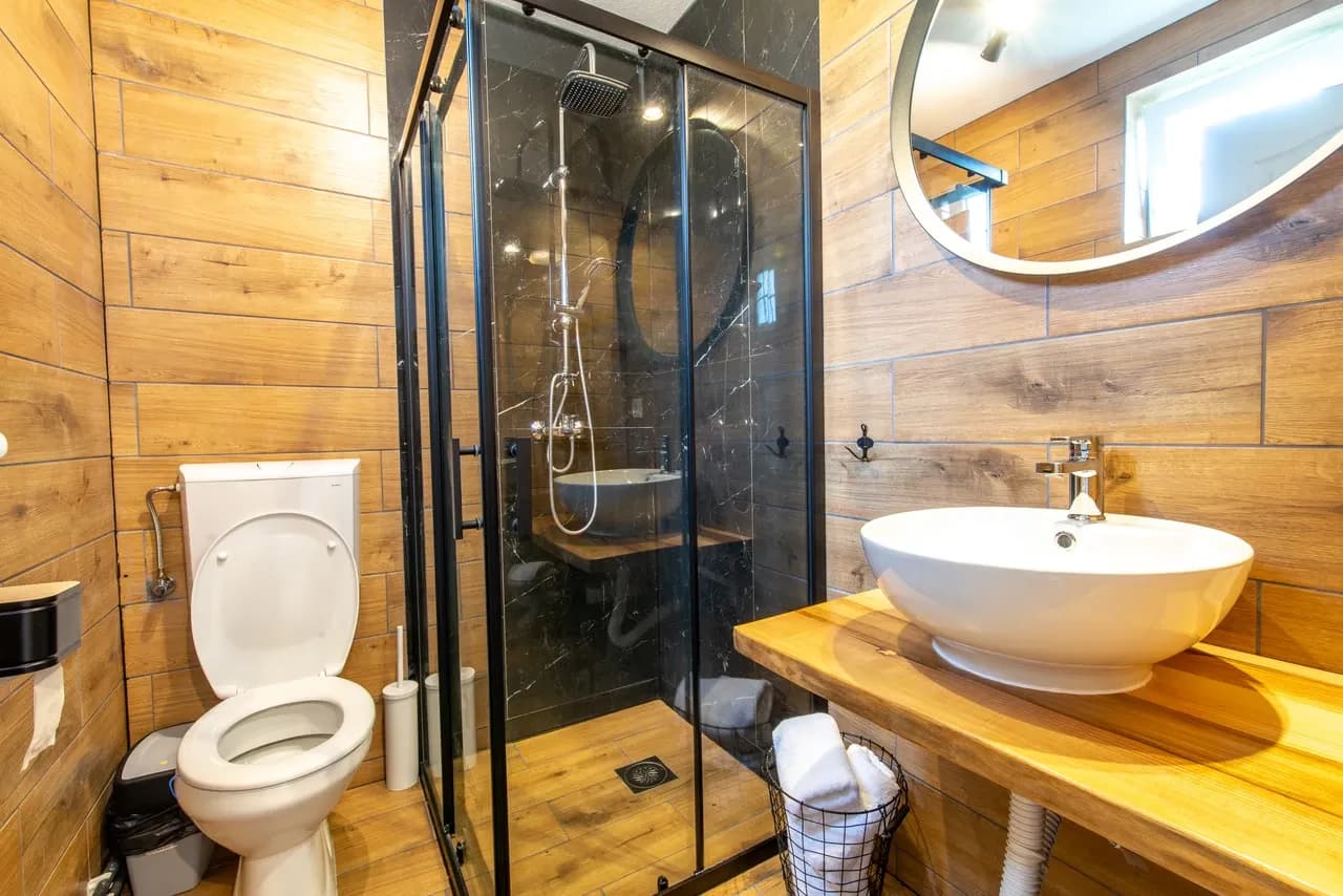 Bathroom with wood-effect wall finishes, glass shower enclosure and basin, photographed in September 2021