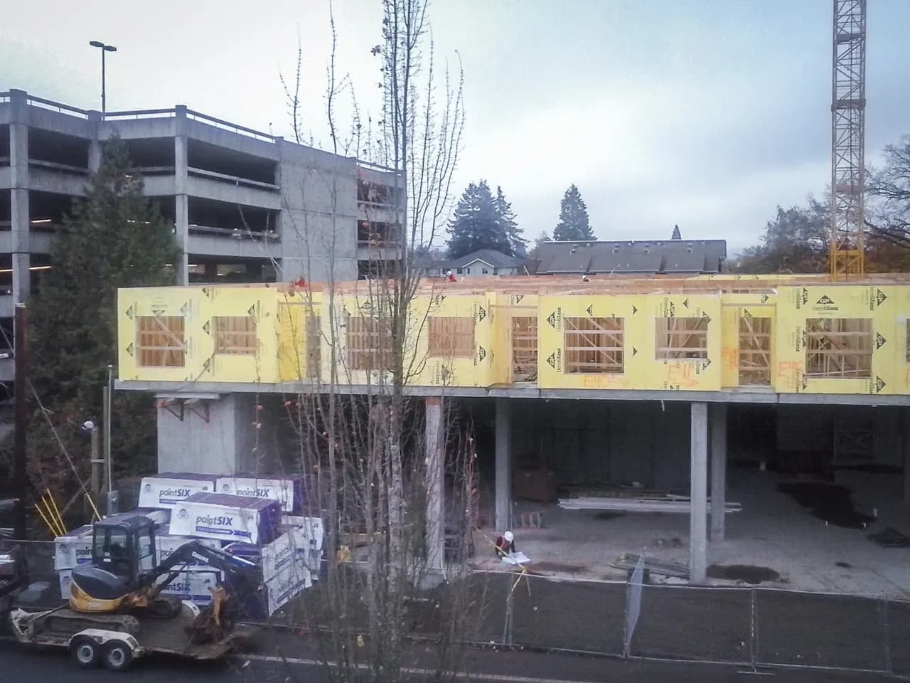 Worker looking at drawings beside a partly built structure in Eugene, Oregon, photographed in November 2013