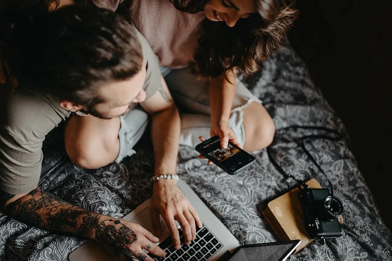 Two people looking at a laptop and smartphone together, May 2024 illustrative photograph