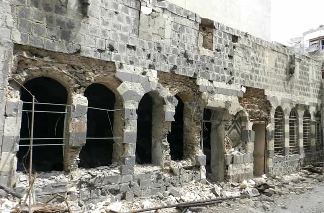 Damaged stone facade and arched openings in Bab Dreeb, Homs, April 2012
