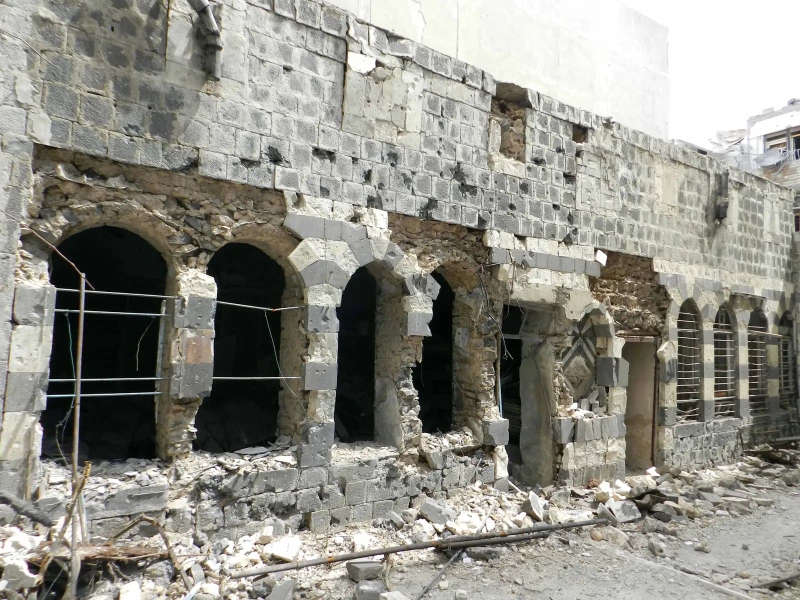 Damaged stone facade and arched openings in Bab Dreeb, Homs, April 2012