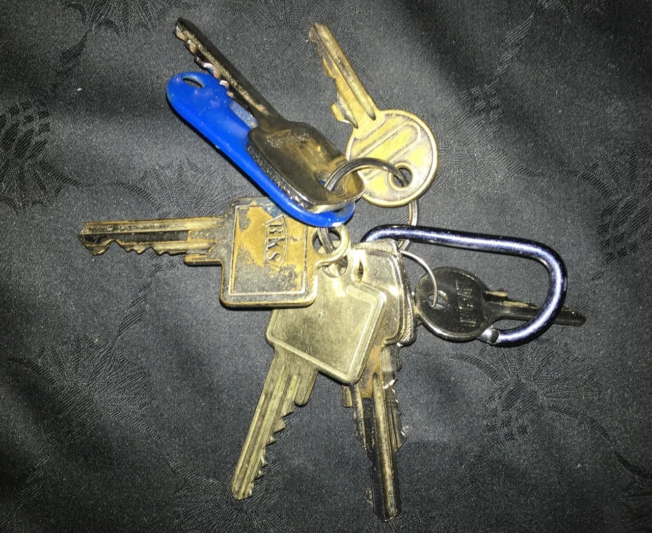 Several metal keys and a blue plastic tag on a keyring, photographed in November 2022