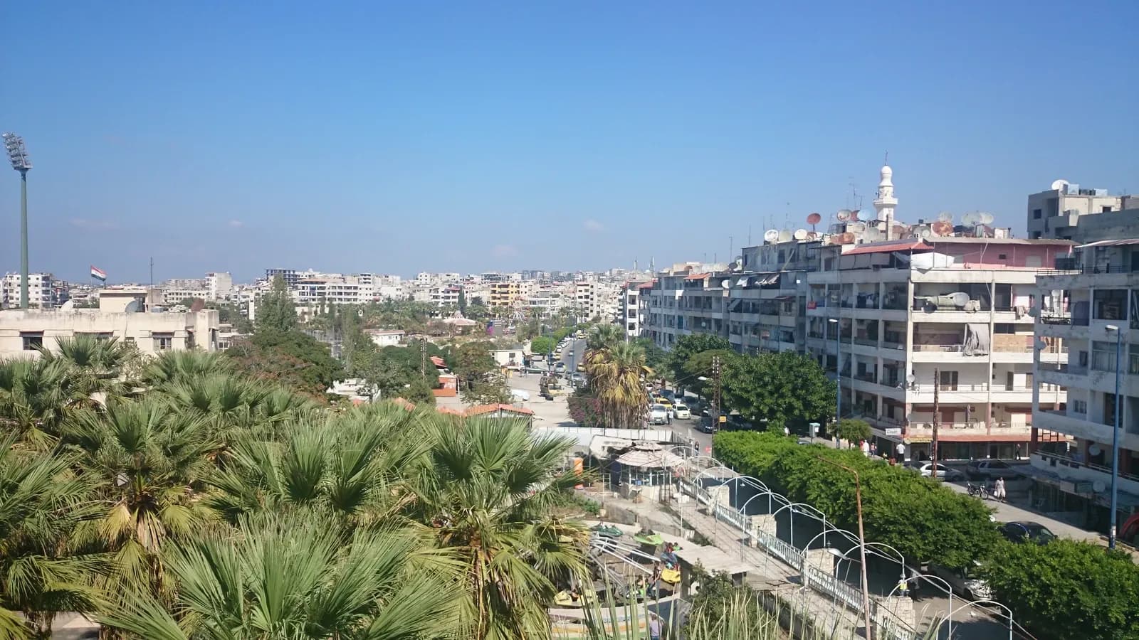 Multi-storey buildings, balconies and a palm-lined urban street in Latakia, November 2014