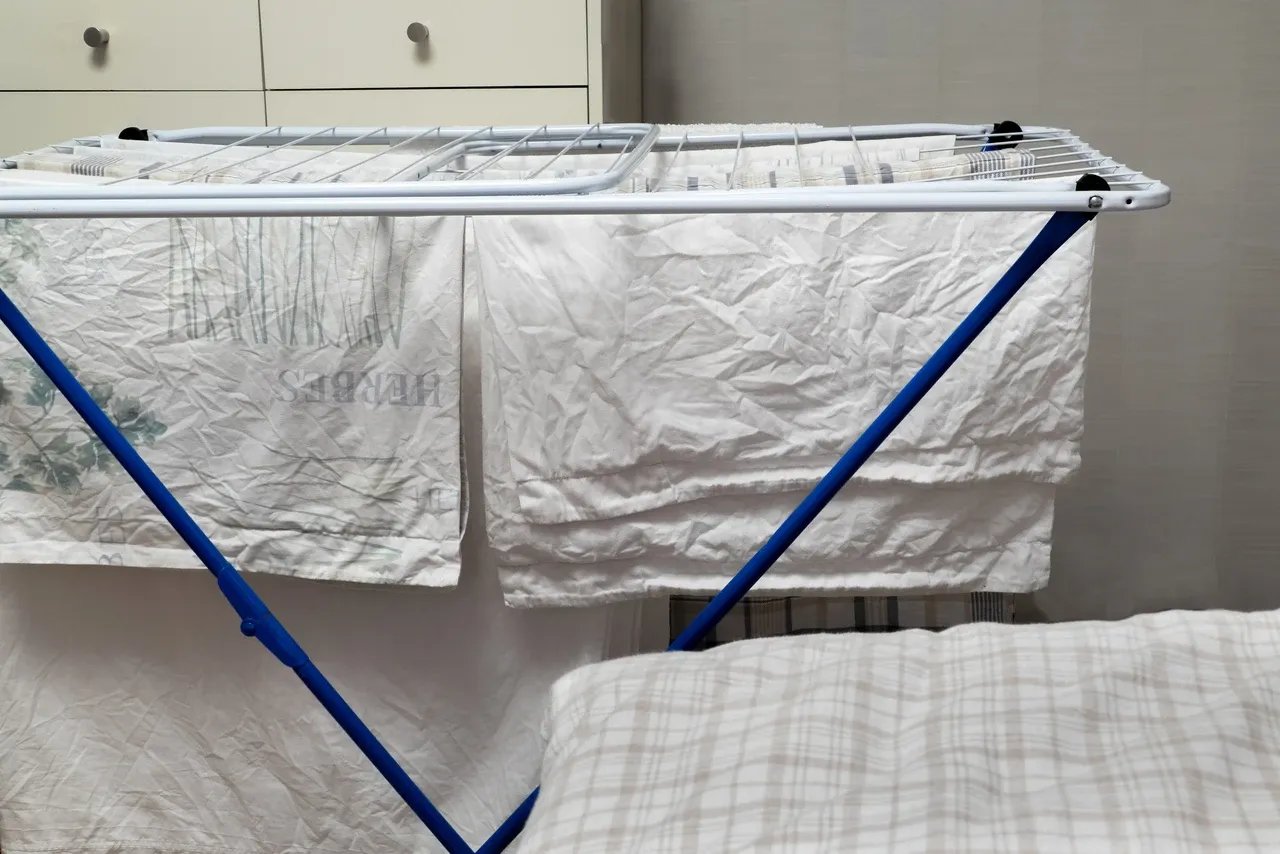 Bed linen hanging on a blue-legged drying rack in a room in Brastad, Sweden, photographed in December 2022