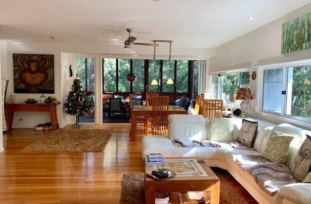Sofa, coffee table and dining furniture beside large windows in an open-plan Noosa North Shore house, photographed in January 2019