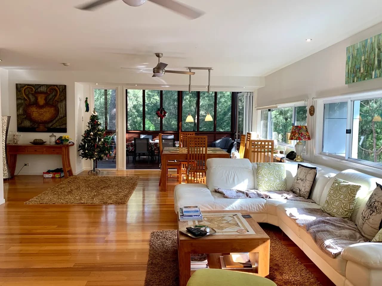 Sofa, coffee table and dining furniture beside large windows in an open-plan Noosa North Shore house, photographed in January 2019