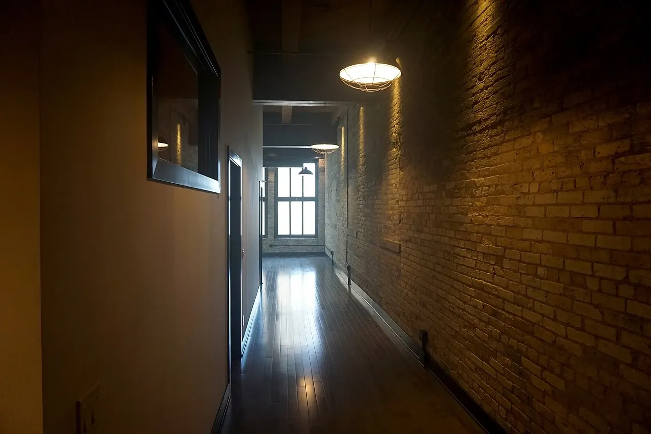 Long apartment passage with exposed brick, doors and ceiling lights at the Pritzlaff Building in Milwaukee, Wisconsin, United States