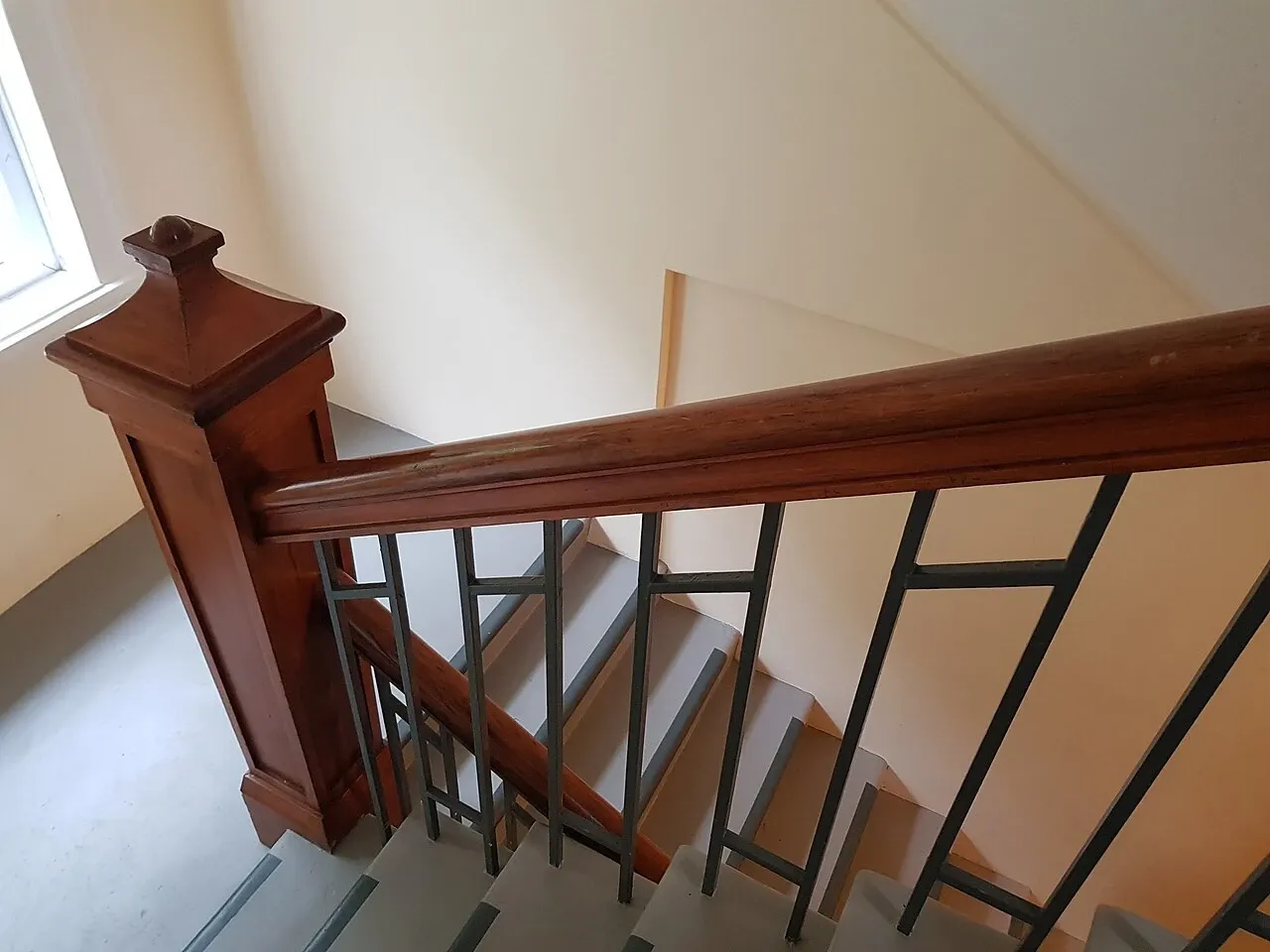 Shared staircase with wooden handrail and a landing window at Chevening Flats