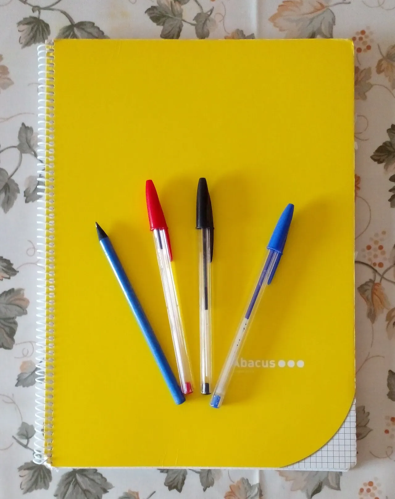 Yellow notebook with several pens and a pencil