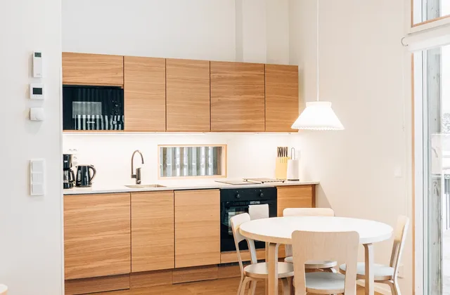 Kitchen and dining space with white cabinets and a wooden table in Finland