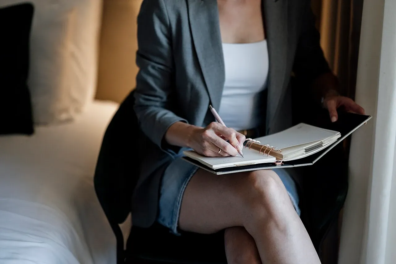 Woman sitting in a chair and writing in a notebook