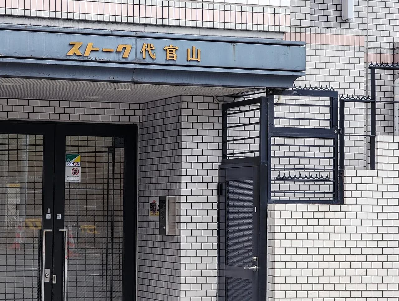 Tiled residential entrance with a door and signage near Daikanyama, Japan