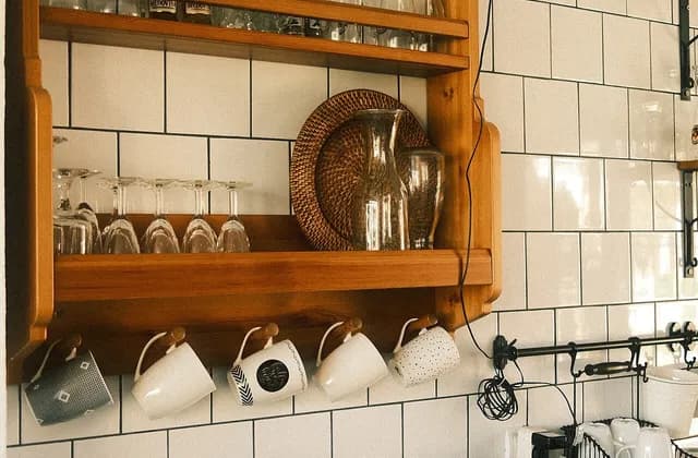 Kitchen shelving with glassware above a tiled counter and sink