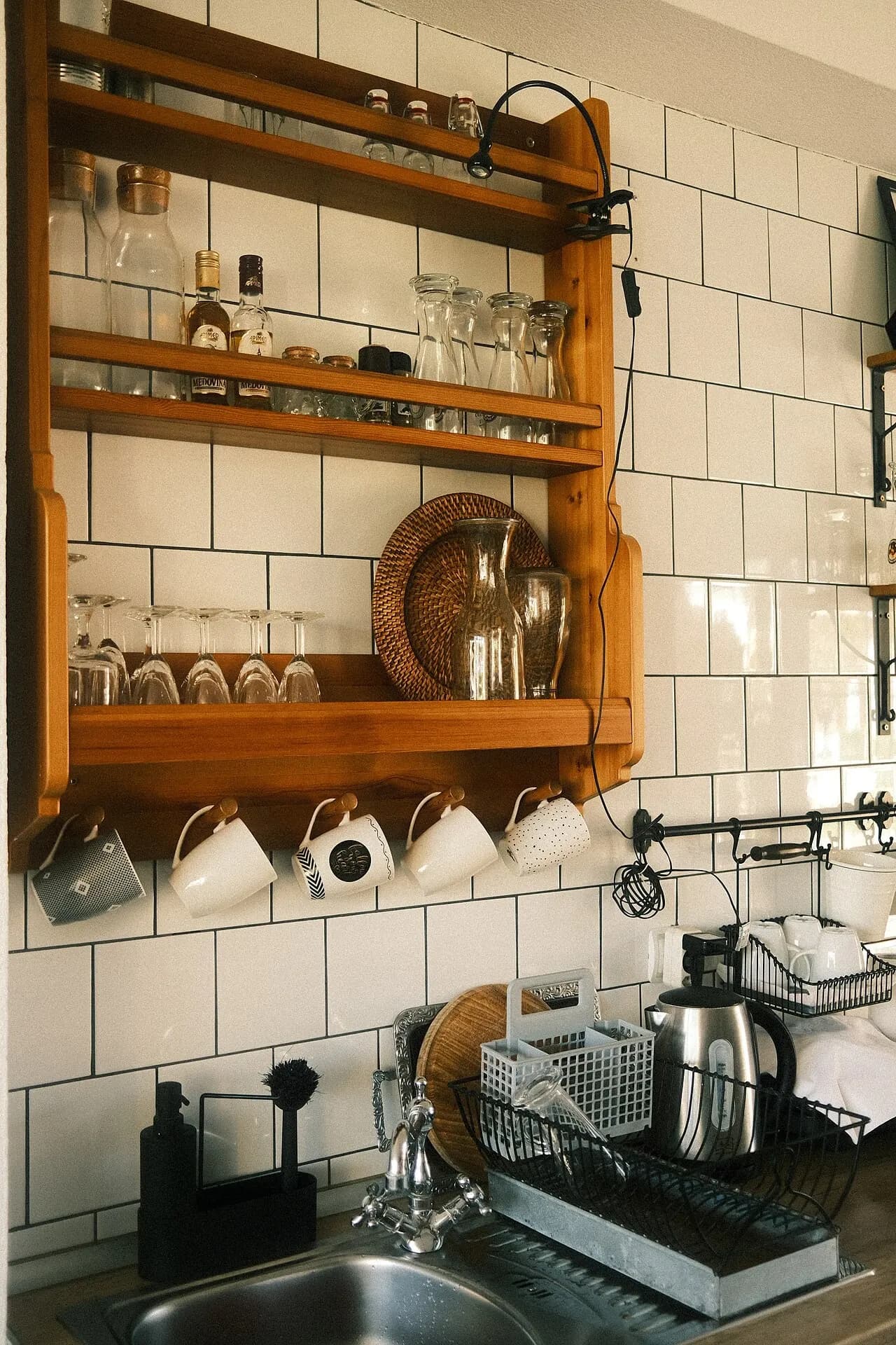 Kitchen shelving with glassware above a tiled counter and sink