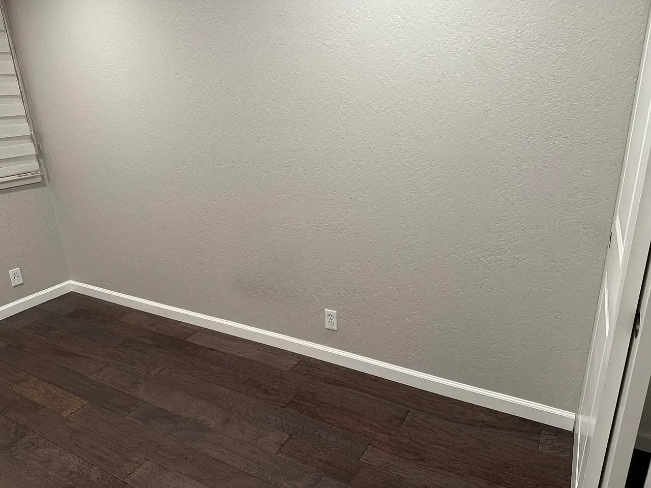 Unfurnished room corner with a window blind and wall socket