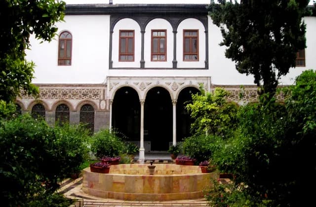 Courtyard of Maktab Anbar in Damascus, with a fountain, planting and arched openings, archive 2009