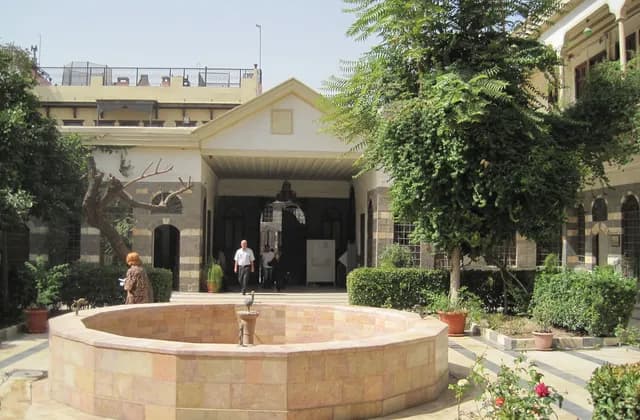 Reception courtyard at Maktab Anbar in Damascus, with a circular basin, trees and surrounding facades, October 2010