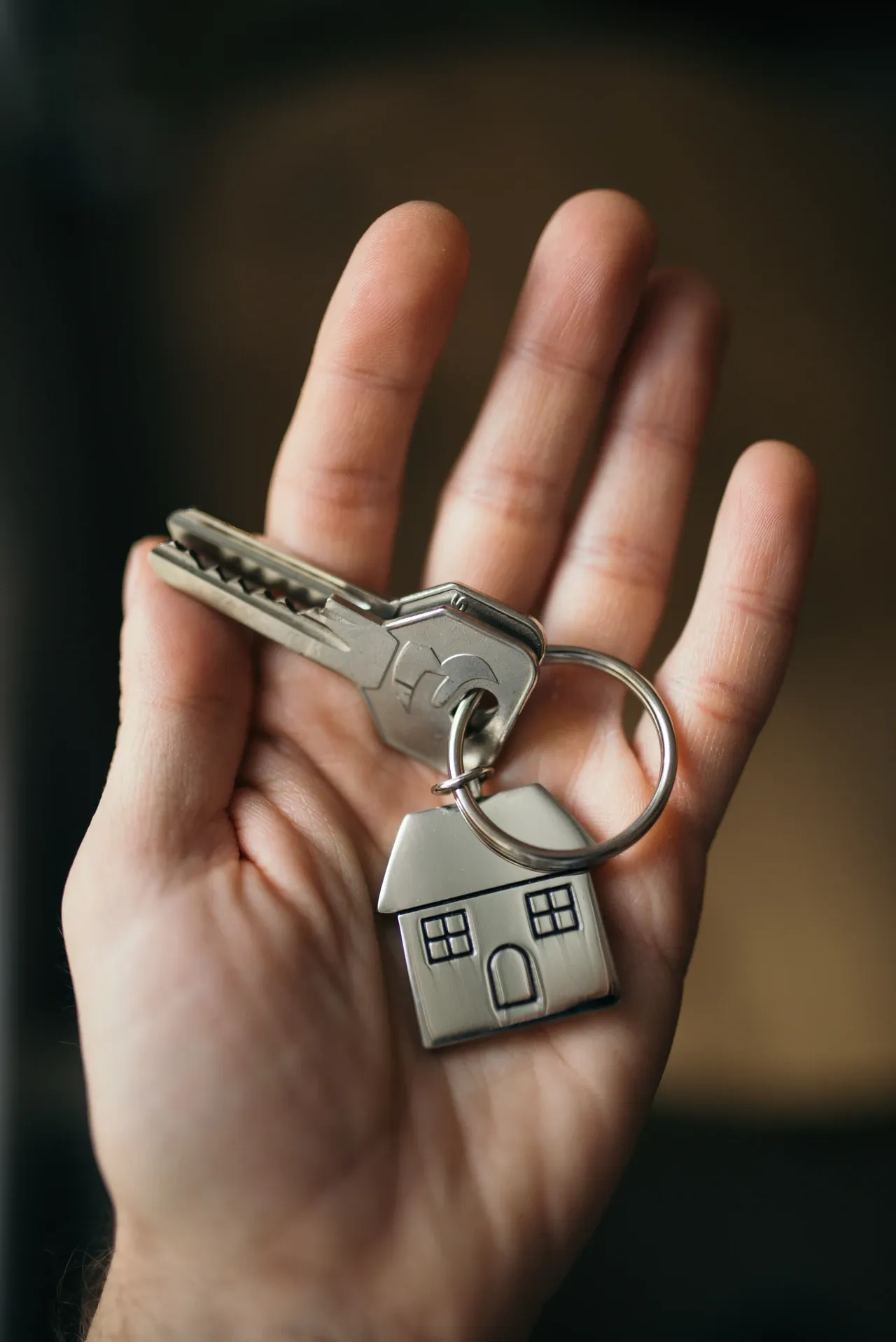 Hand holding metal keys and a house-shaped keyring, photographed in November 2020