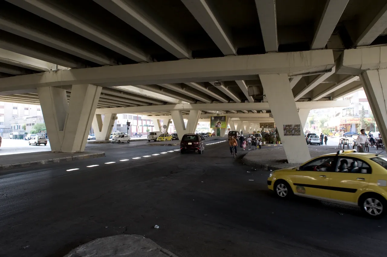 Vehicles and pedestrians beneath an elevated road in Damascus al-Midan, photographed in September 2008