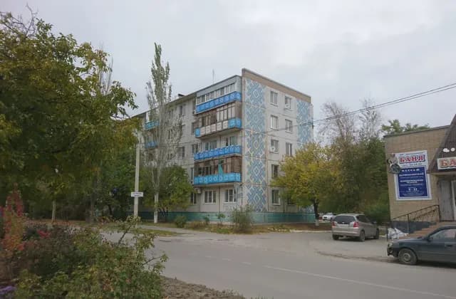 Apartment building with patterned balcony panels beside a separate sauna building in Volgodonsk, Russia