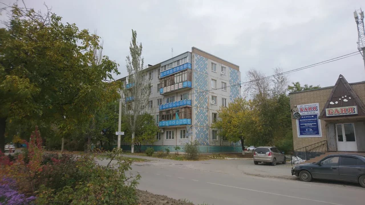 Apartment building with patterned balcony panels beside a separate sauna building in Volgodonsk, Russia