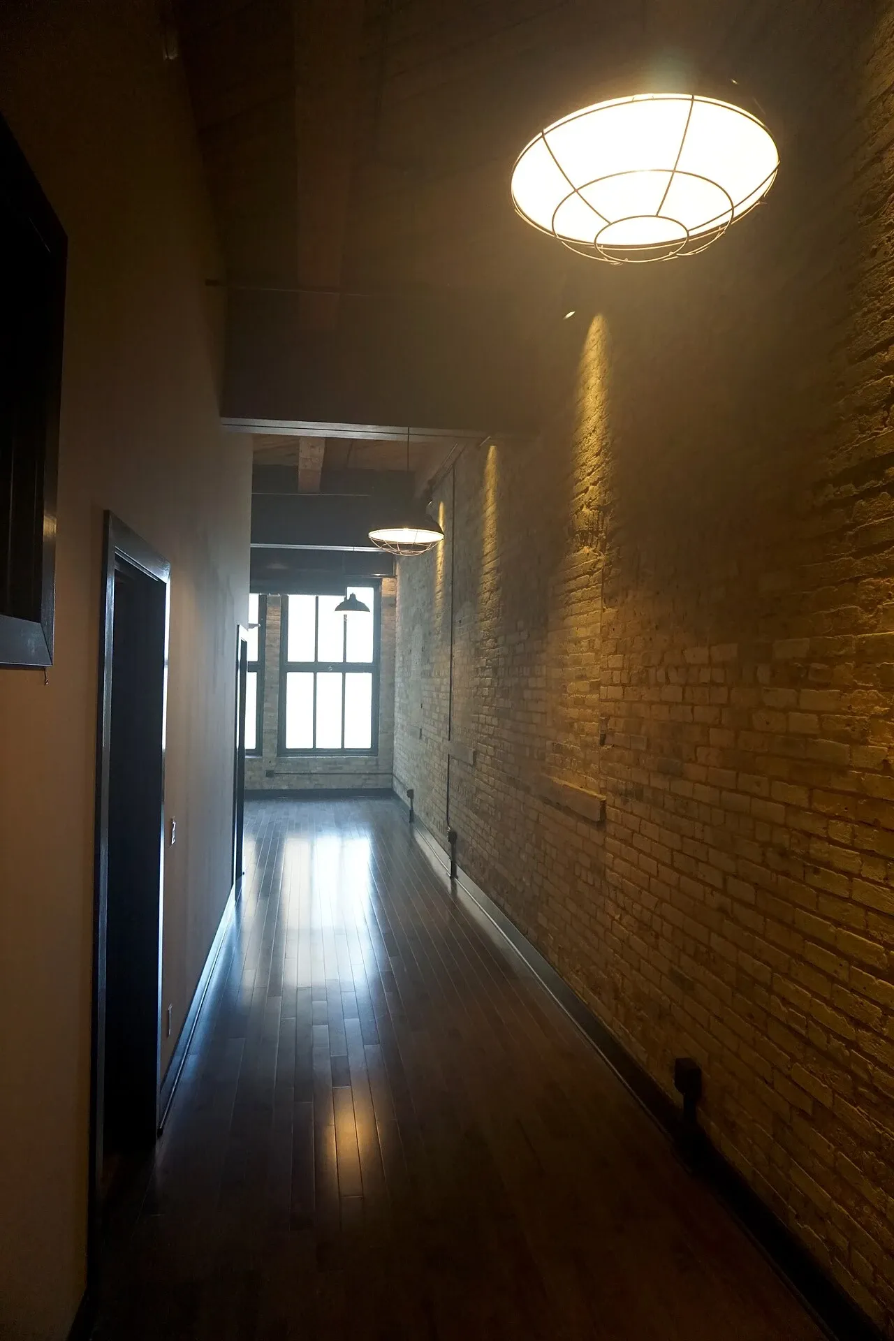 Apartment passage with exposed brick, glazed doors and ceiling lights at the Pritzlaff Building in Milwaukee, Wisconsin, United States