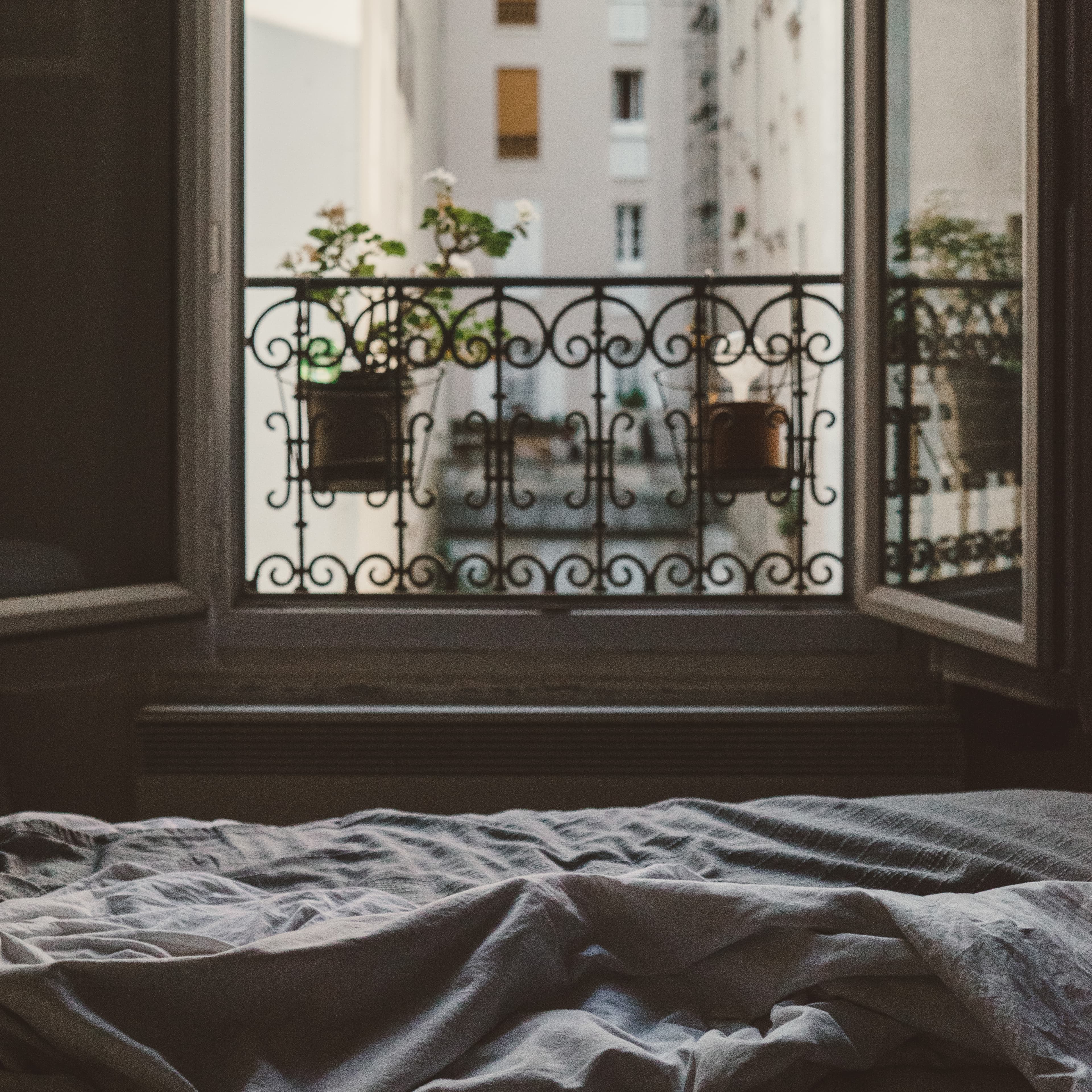 Open bedroom window overlooking a balcony in Paris