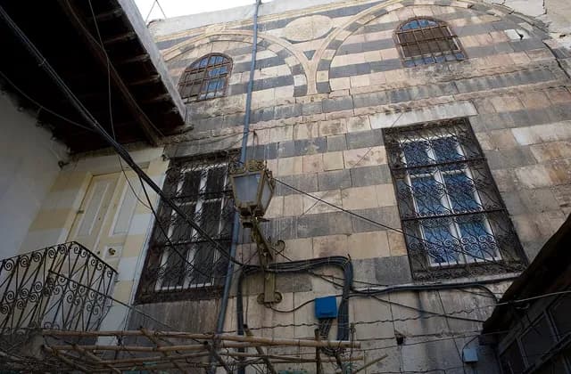 Alternating light and dark masonry and barred windows on a Damascus building, photographed in September 2008
