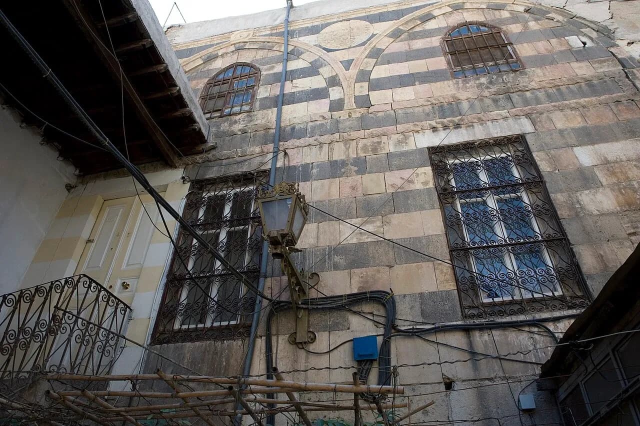Alternating light and dark masonry and barred windows on a Damascus building, photographed in September 2008