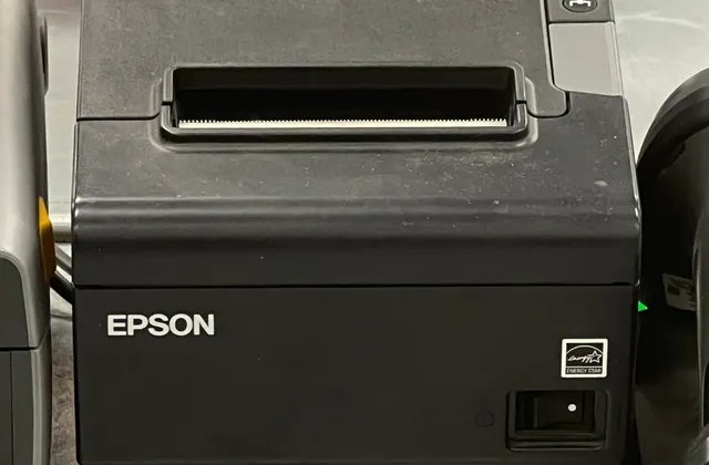 Black receipt printer on a counter, photographed in June 2026
