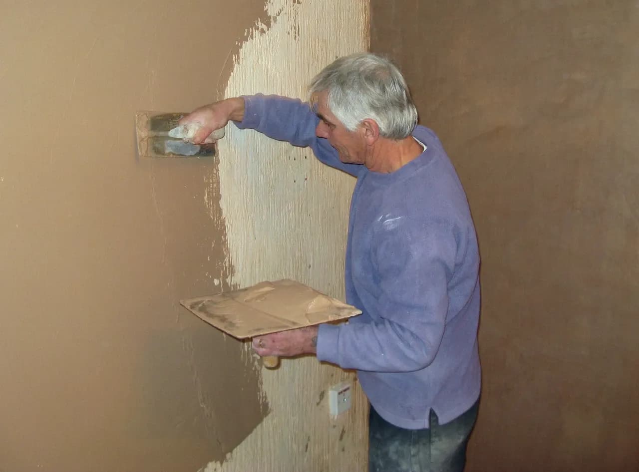 Plasterer applying plaster to a wall in Yate, England, photographed in 2009