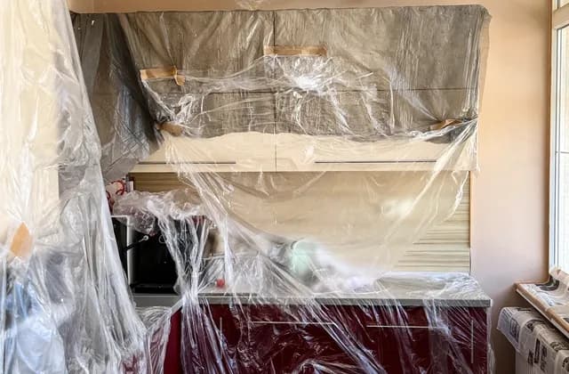 Kitchen fittings and furniture covered with plastic during preparation for decoration, photographed in May 2026