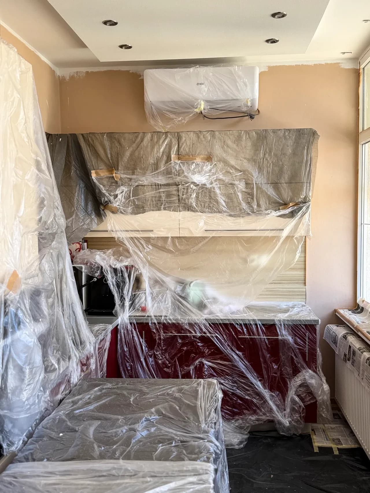 Kitchen fittings and furniture covered with plastic during preparation for decoration, photographed in May 2026