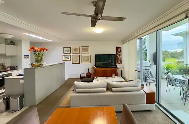 Lounge with kitchen opening and glazed balcony doors in a Brisbane apartment, June 2025