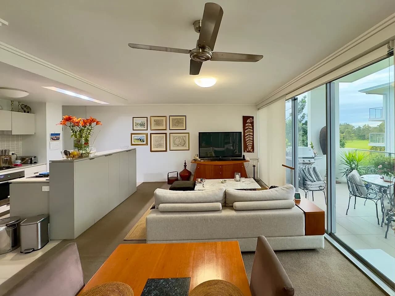 Lounge with kitchen opening and glazed balcony doors in a Brisbane apartment, June 2025